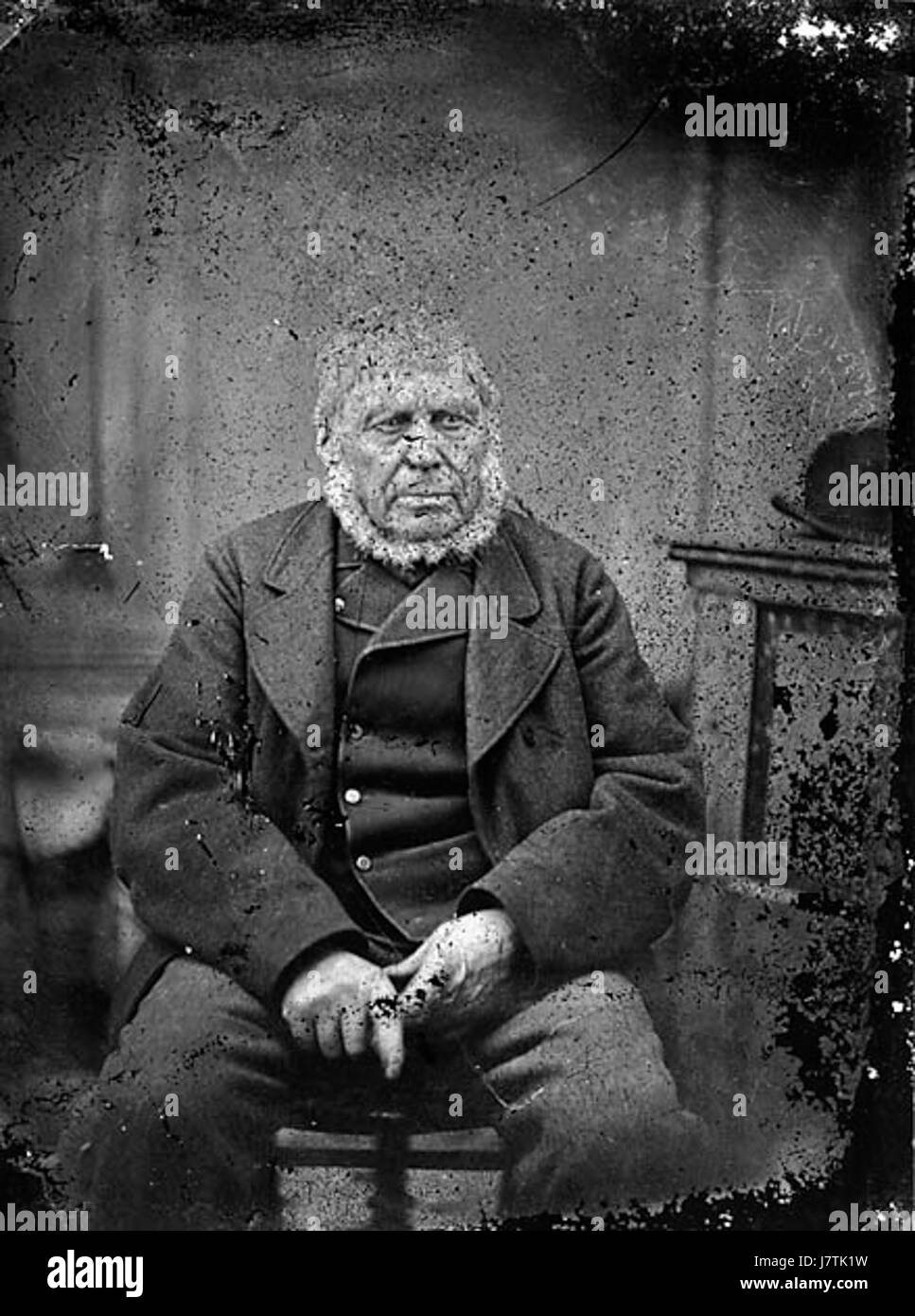 Questa immagine raffigura un uomo anziano seduto, probabilmente catturato in un momento riflettente o in un ambiente tradizionale, che mostra gli aspetti tranquilli dell'invecchiamento e della contemplazione. Foto Stock