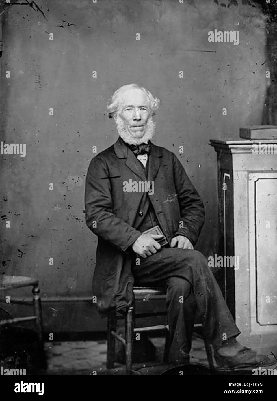 Un vecchio uomo seduto e in possesso di un libro NLW3364987 Foto Stock