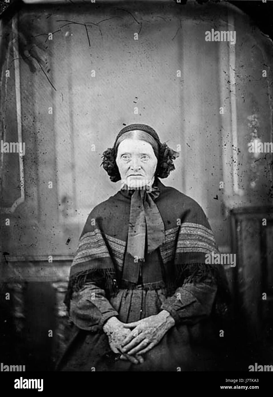 Una vecchia donna seduta e indossando un cofano NLW3364968 Foto Stock