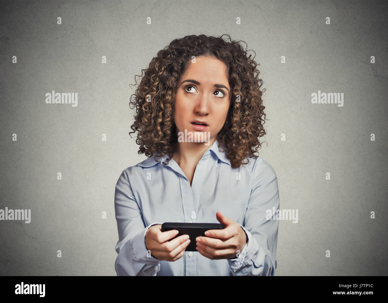Ritratto confuso scettici donna infelice sms sul cellulare orinato con conversazioni di decidere sulla risposta isolato muro grigio Sfondo. Negati Foto Stock