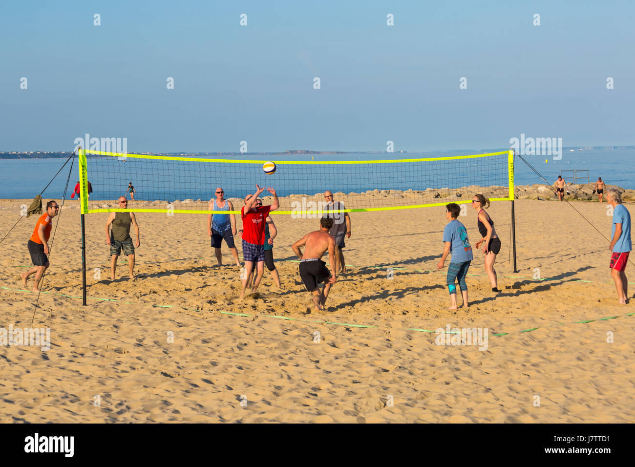 Le persone aventi divertirsi giocando a pallavolo in spiaggia a banchi di sabbia spiaggia, Poole, Dorset nel Maggio Foto Stock