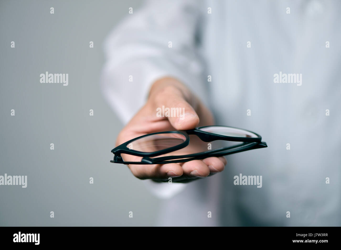 Primo piano di un giovane uomo ottico in un manto bianco di portare un paio di occhiali per l'osservatore Foto Stock