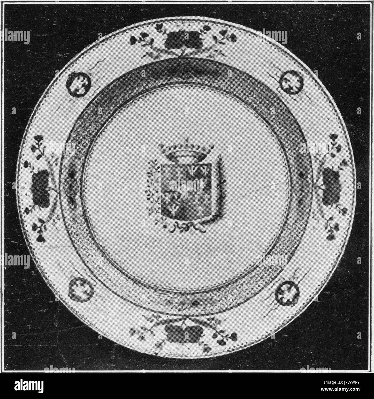 Questo grande piatto presenta uno stemma, che probabilmente significa una famiglia nobile o reale. L'intricato design del piatto riflette la tradizione araldica di rappresentare l'identità familiare o regionale attraverso simboli e colori. Foto Stock