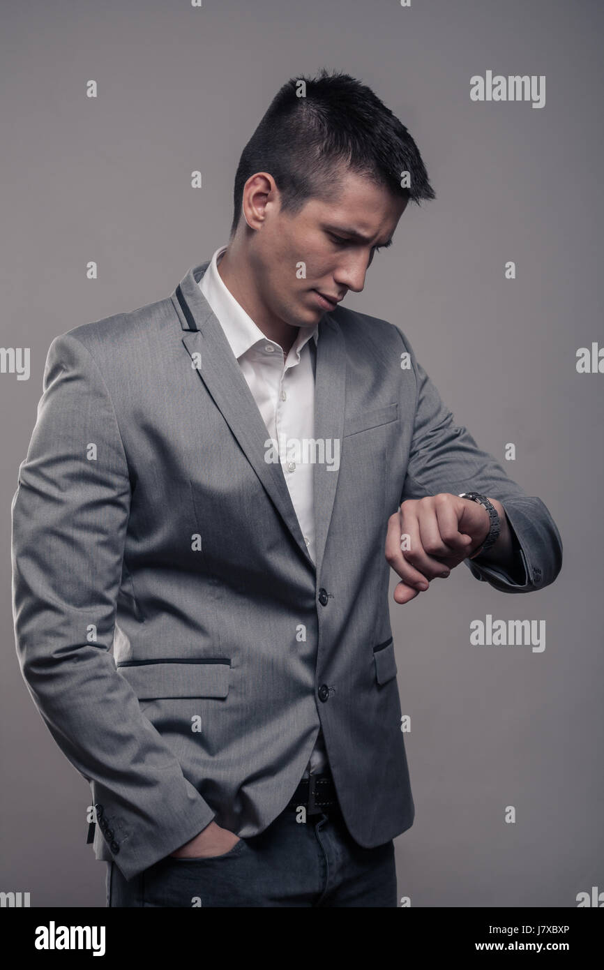 Un giovane uomo adulto, abiti formali, cappotto, una camicia bianca, la parte superiore del corpo e sfondo grigio, studio, guardando a guardare Foto Stock