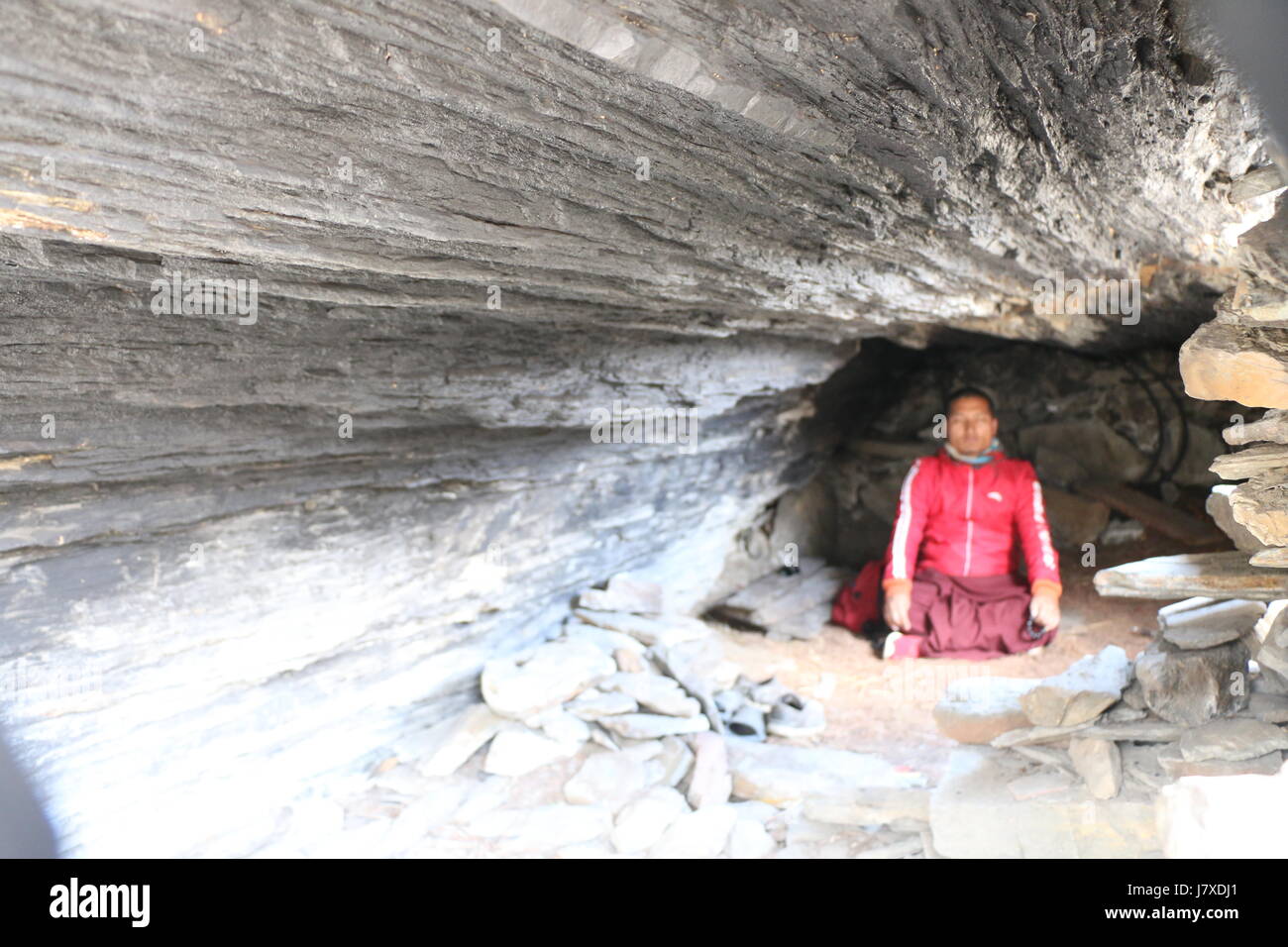 Un monaco meditando nella grotta , Foto Stock