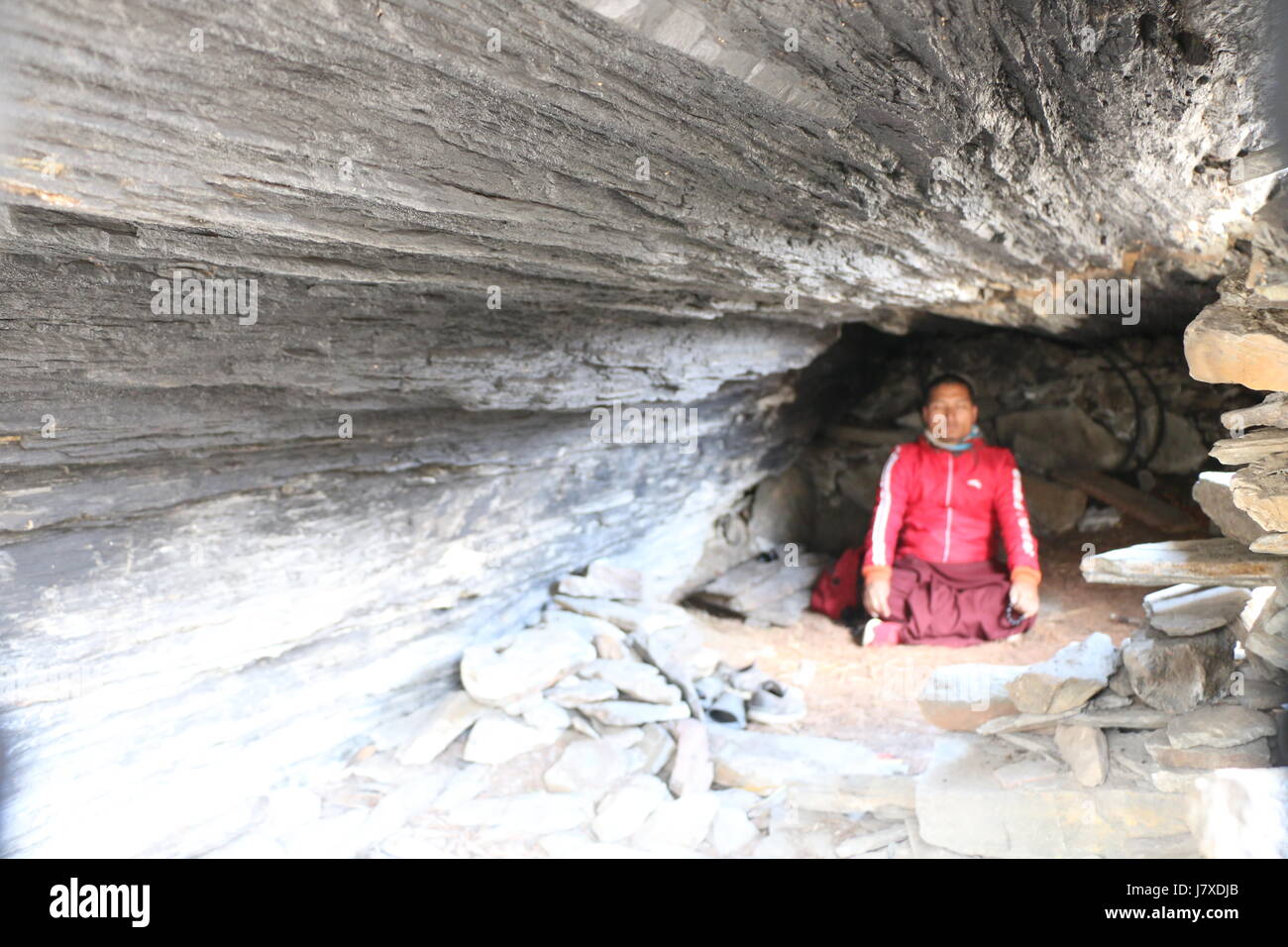Un monaco meditando nella grotta , Foto Stock