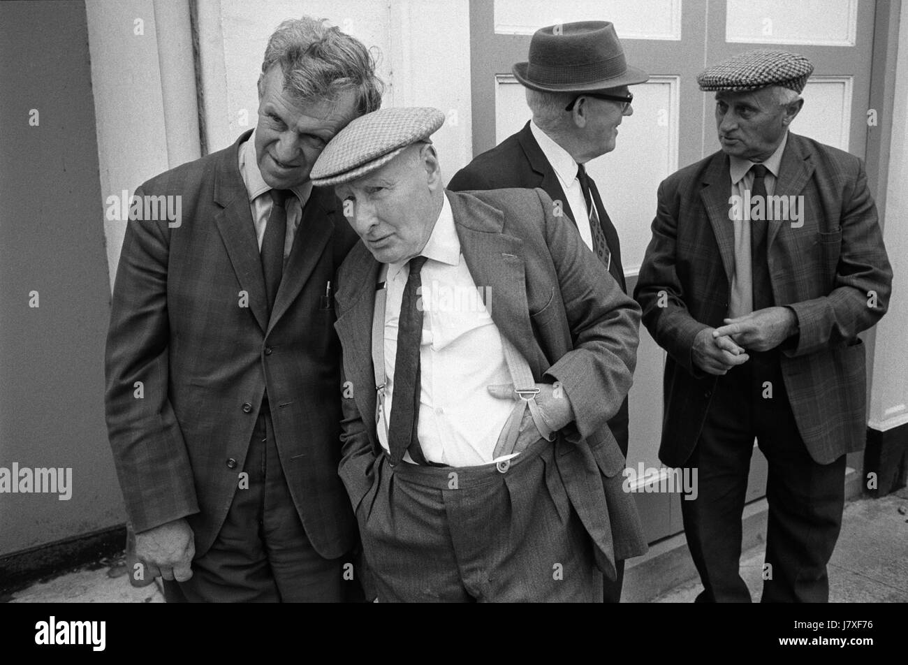Amici amicizia gruppo di uomini che parlano insieme vita di villaggio Regno Unito Inghilterra anni '1970 guardando la graziosa processione annuale della Maid of Holsworthy, Holsworthy, Devon Inghilterra 1975 HOMER SYKES Foto Stock