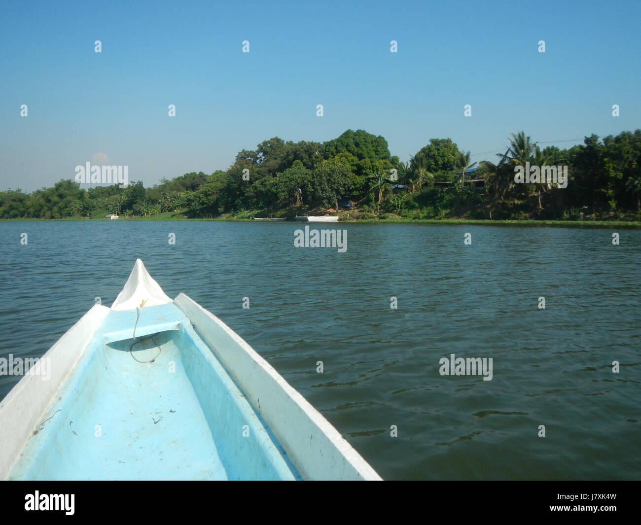 L'immagine raffigura Pulilan e Plaridel a Bulacan, che mostrano sponde del fiume, alberi e costruzioni di riprap insieme a barche utilizzate per il trasporto nella regione. Il paesaggio mette in evidenza il collegamento tra l'insediamento umano, la natura e la gestione delle vie navigabili in questa zona di Bulacan. Foto Stock