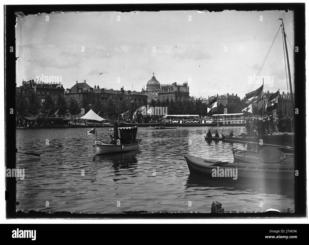 "Amstel tijdens roeiwedstrijd" di Jacob Olie cattura una corsa a remi sul fiume Amstel. Questa fotografia storica raffigura la natura competitiva degli sport di canottaggio nei Paesi Bassi, mostrando gli atleti durante una gara intensa. Foto Stock