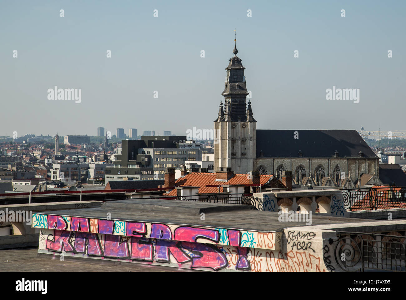 Un tetto con vista sullo skyline di Bruxelles, con alcuni arte di strada in primo piano e il contorno di una cattedrale in background. Foto Stock