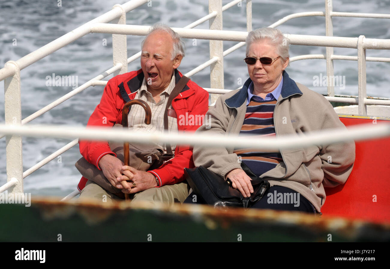 Uomo anziano a sbadigliare mentre seduto sul traghetto con la signora anziana coppia ri coppie seniores pensionamento REGNO UNITO Foto Stock
