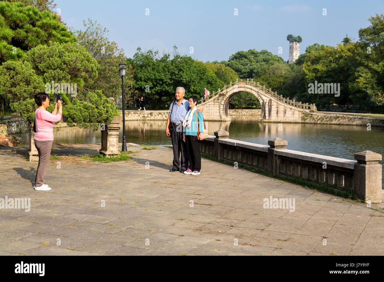 Wenzhou, Zhejiang, Cina. Jiangxin isola. Di mezza età matura che è fotografata davanti al Ponte della Luna. Oriente Pagoda in background, ricostruita 11 Foto Stock
