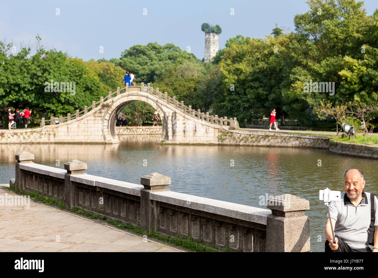 Wenzhou, Zhejiang, Cina. Jiangxin isola. Visitatore cinese facendo una Selfie dalla Luna Bridge. Oriente Pagoda in background, ricostruita 1141. Foto Stock
