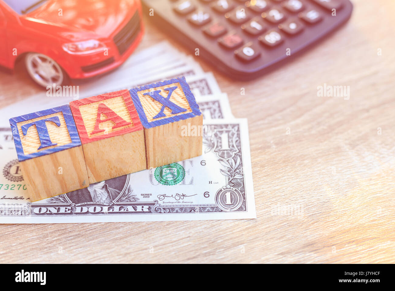 Tassa write in alfabeto colore scatola di legno sul dollaro Usa e auto rossa, calcolatrice. Per il momento di pagare il concetto fiscale Foto Stock