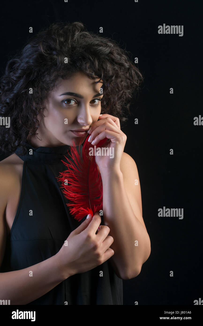 Bella giovane donna tenendo un red feather Foto Stock