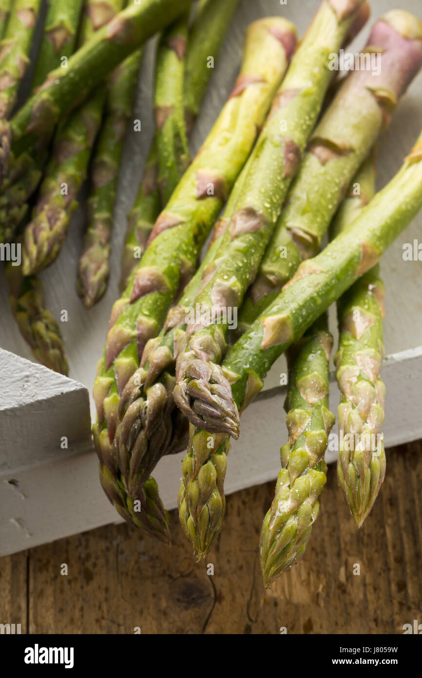Bundle di Fresh cut materie non cotti asparagi verdi vegetale nel riquadro bianco sul tavolo rustico sfondo Foto Stock