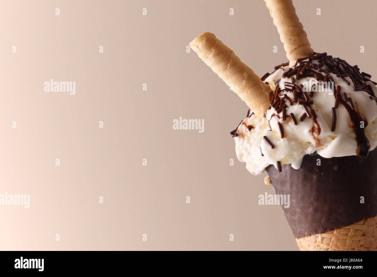 Cono gelato aromatizzato cream choco vicino. Guarnito con cioccolato tagliatelle e wafer. Con sfondo marrone. Composizione orizzontale. Foto Stock