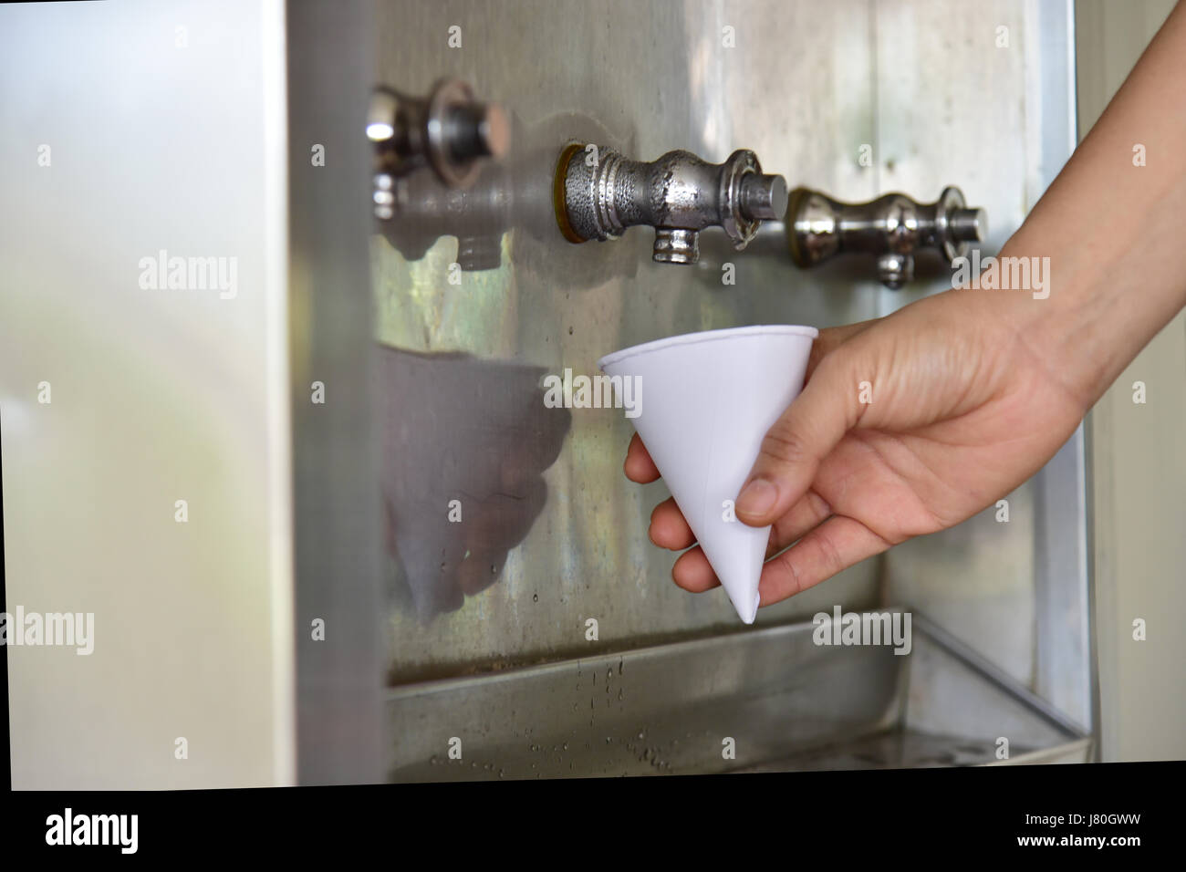 L uomo come ottenere un freddo, bevanda rinfrescante dal radiatore dell'acqua. Foto Stock
