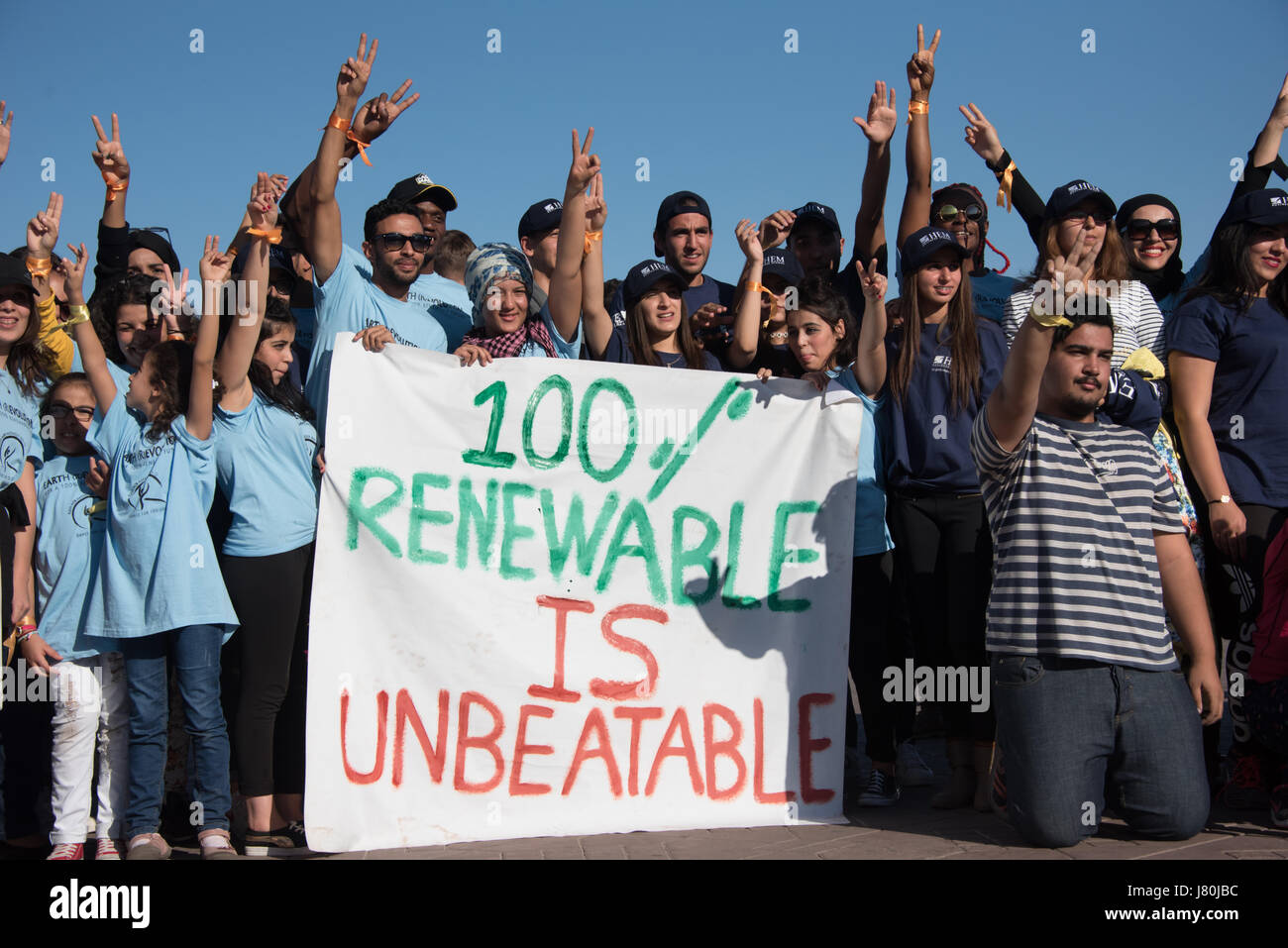 Giovani attivisti al COP22 conferenza ONU sul clima di tenere un segno a leggere '100% di energia rinnovabile è imbattibile" in occasione di una manifestazione di piazza Jemaa El Fnaa, il mercato centrale plaza a Marrakech, Marocco, 10 novembre 2016. Foto Stock