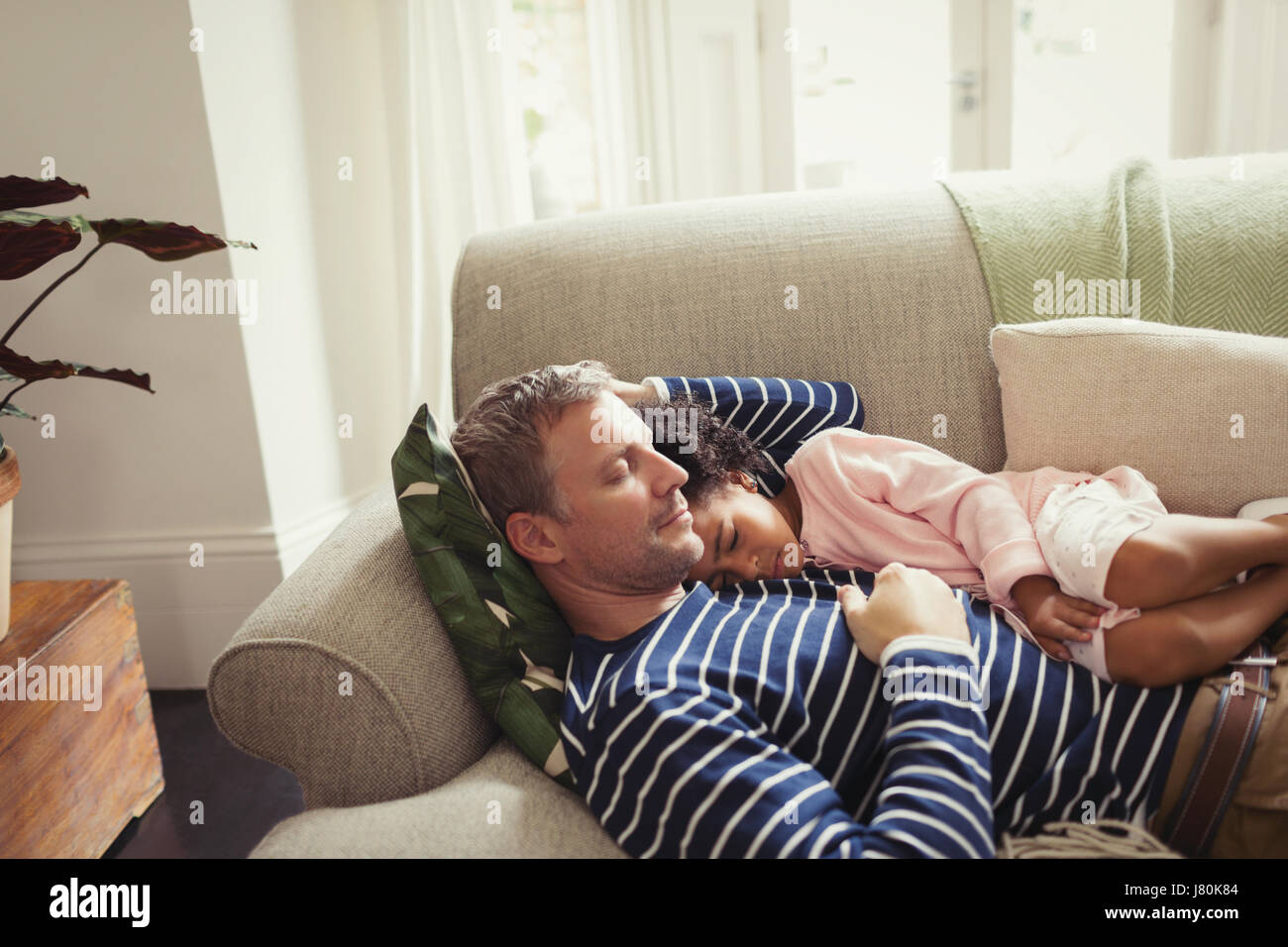 Affettuosa e serena multi-etnico padre e figlia a sonnecchiare sul divano Foto Stock
