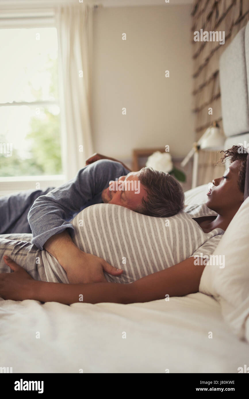 Affettuosa incinta giovane coccole e a sonnecchiare sul letto Foto Stock