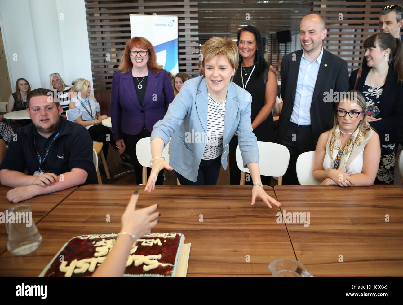 SNP leader Nicola lo storione è presentato con una torta da parte dei lavoratori durante una campagna elettorale visita al gas scozzese HQ di Edimburgo. Foto Stock