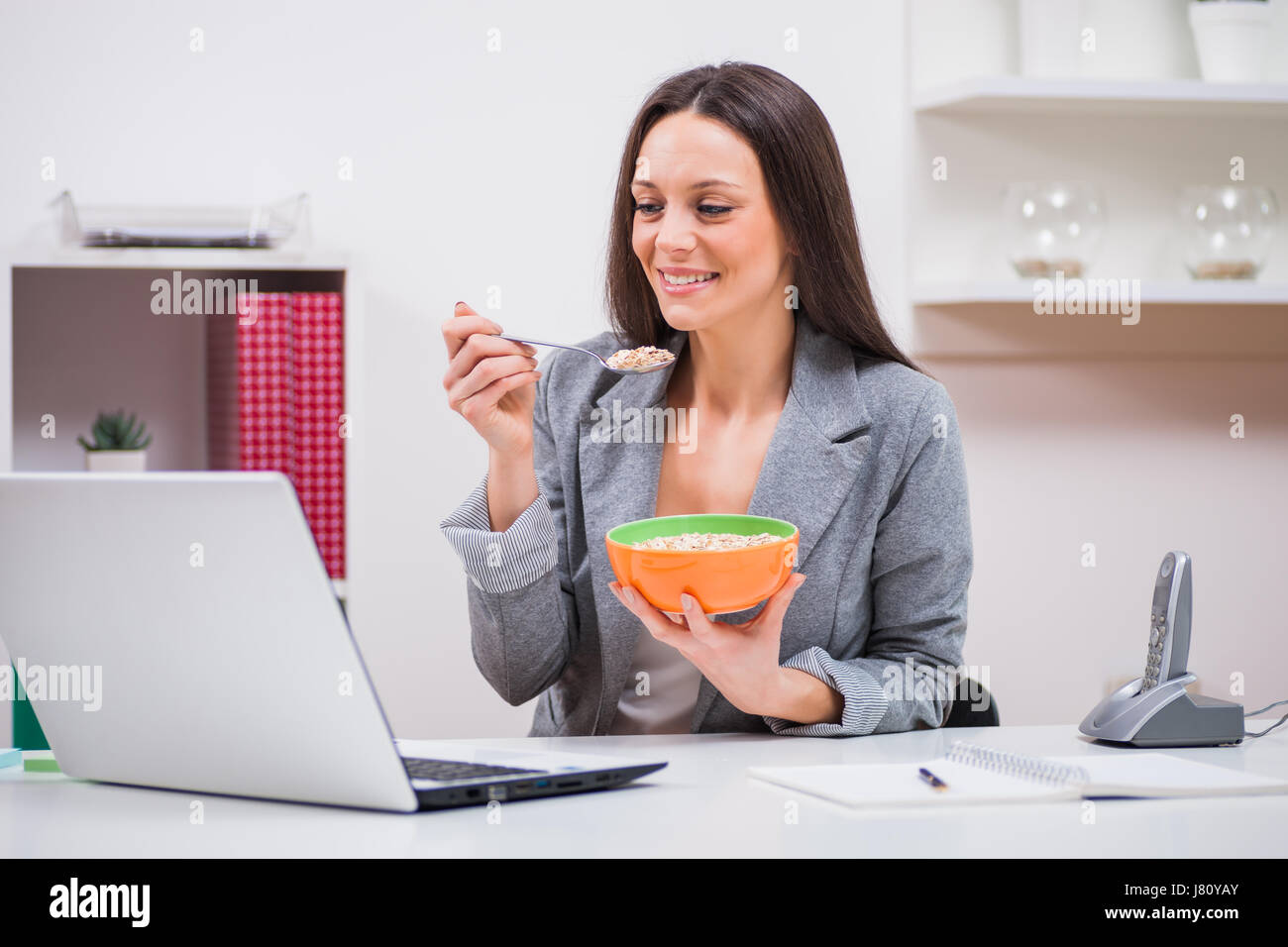 Giovane imprenditrice è mangiare i fiocchi d'avena nel suo ufficio. Foto Stock