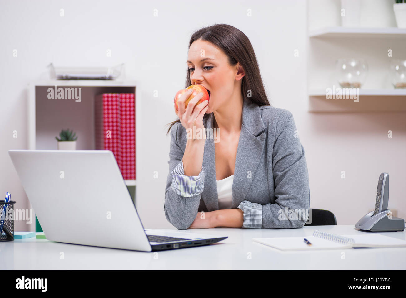 Giovane imprenditrice è mangiare apple nel suo ufficio. Foto Stock