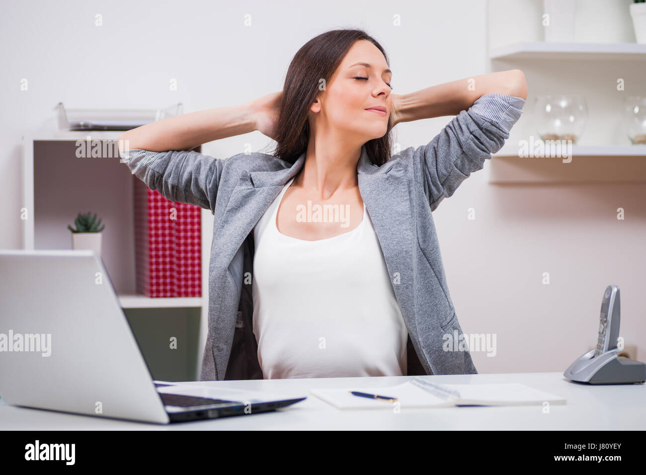 Giovane imprenditrice è rilassante nel suo ufficio. Ella si allunga il suo corpo. Foto Stock