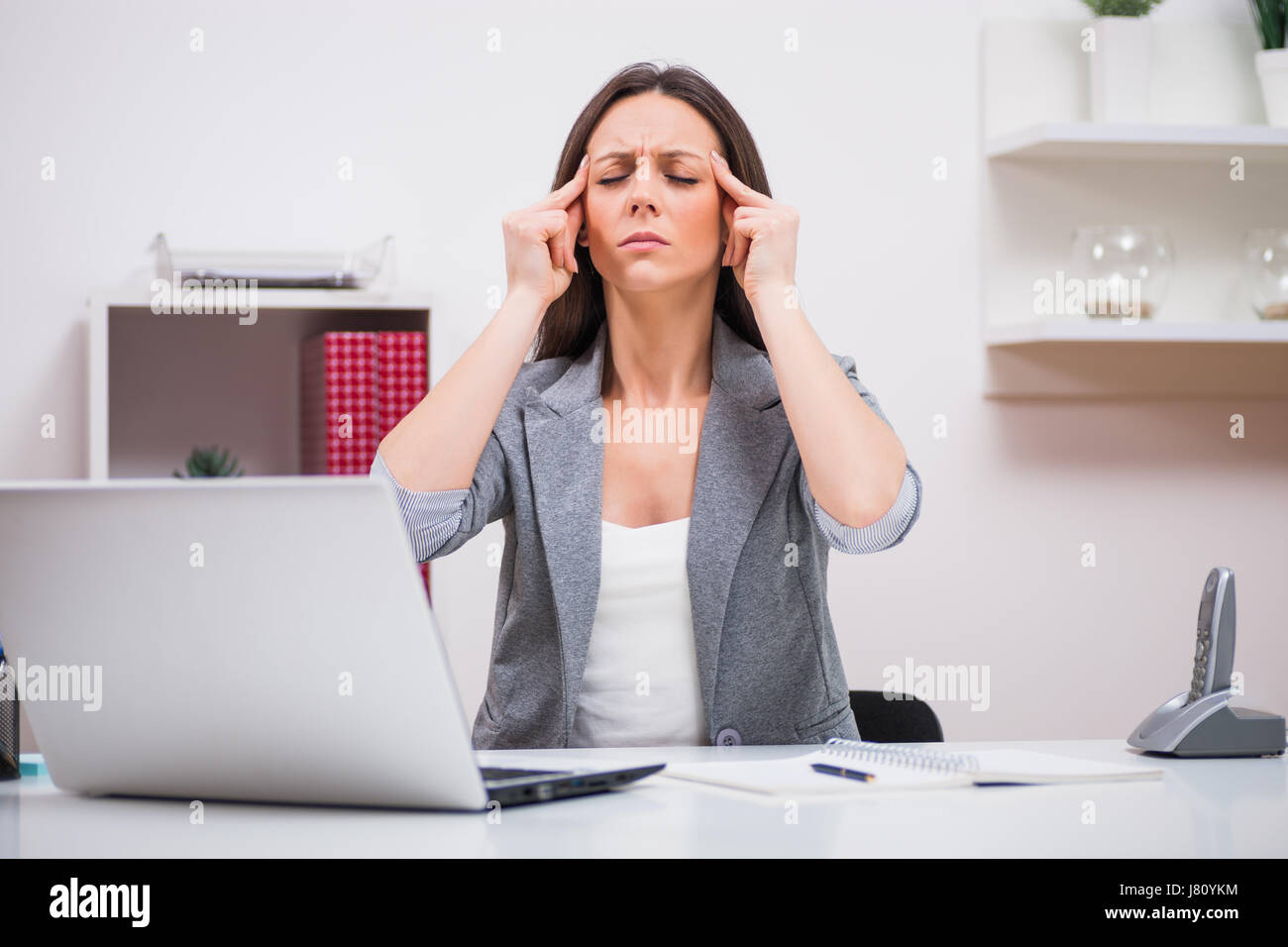 Giovane imprenditrice di avere mal di testa al lavoro. Foto Stock