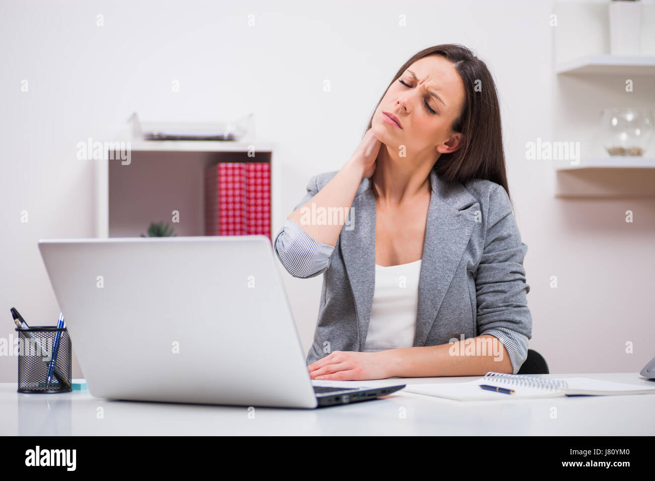 Giovane imprenditrice è avere dolore al collo al lavoro. Foto Stock