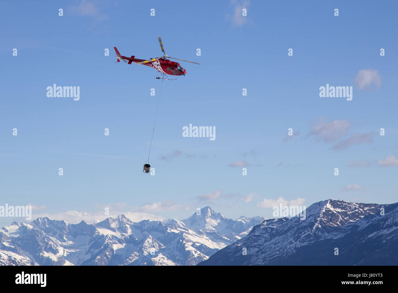 Zermatt, Svizzera - 13 Aprile 2017: un elicottero il trasporto di calcestruzzo per un sito in costruzione nelle montagne svizzere Foto Stock