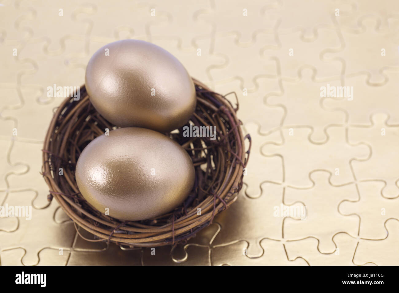 Oro due uova nel nido posto su puzzle mostrano i benefici della costruzione di una forte, il pensionamento portfolio costruito su solidi piani di investimento. Foto Stock