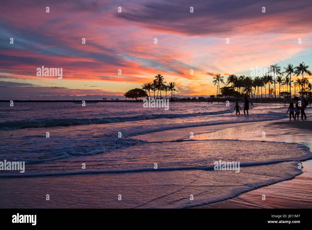 Colorato tramonto dalla spiaggia di fronte all'Hilton Hawaiian Village sulla spiaggia di Waikiki di Oahu. Foto Stock