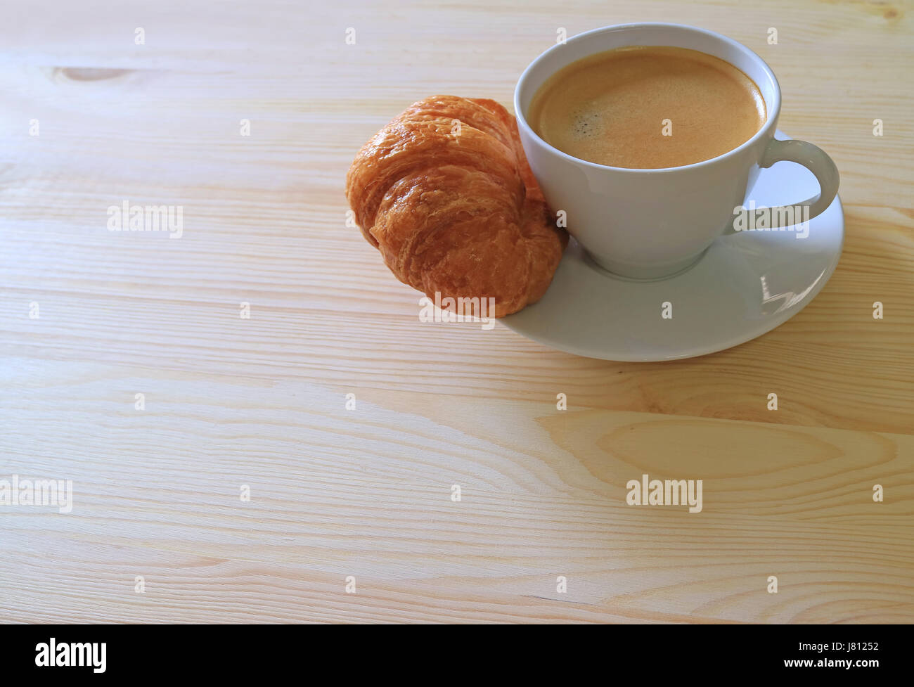 Una tazza di caffè caldo e un croissant al burro sul tavolo di legno, con spazio libero per il testo o per la progettazione Foto Stock