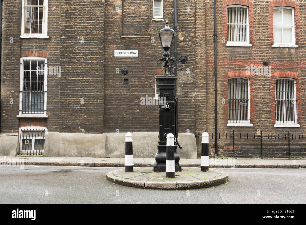 Bedford Row in ghisa pompa acqua e tre paracarri su una piccola isola di fronte Brownlow Street. Foto Stock