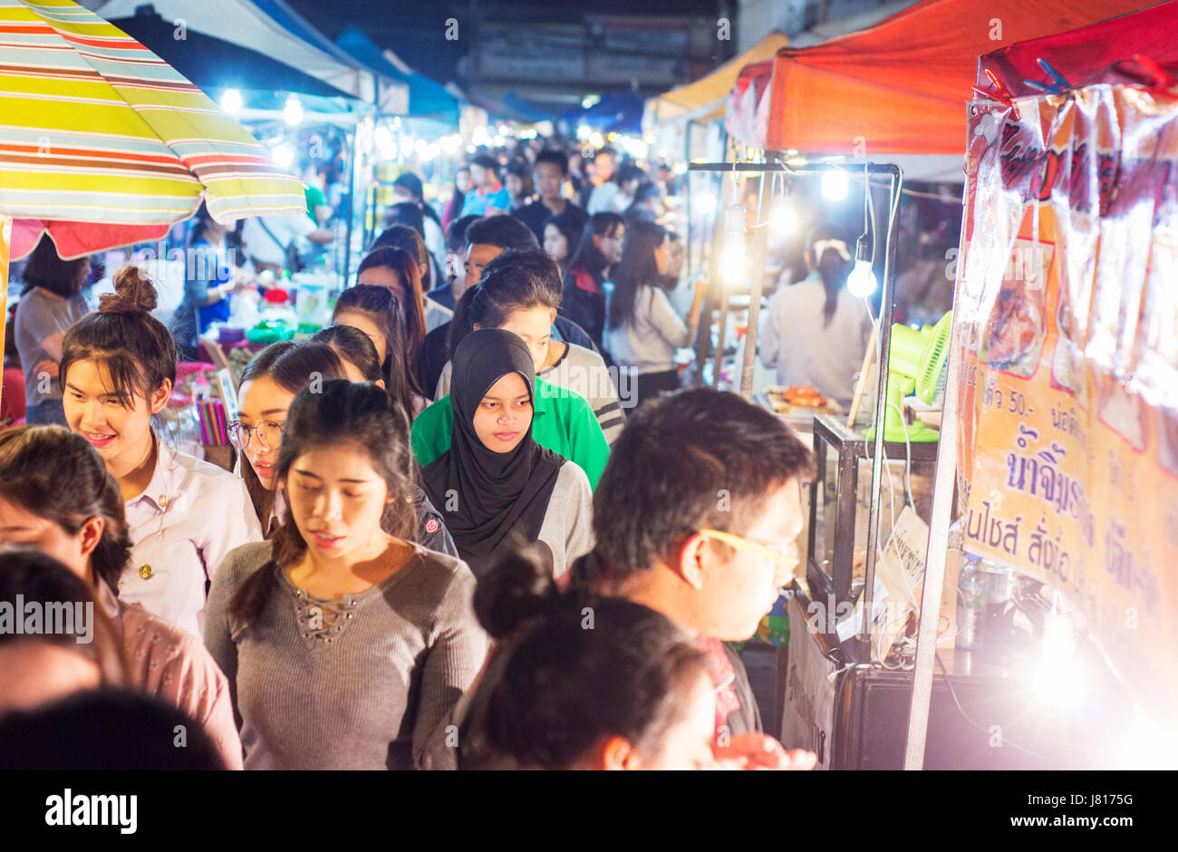 Folle di persone in un mercato notturno vicino a Chiang Rai. Una giovane donna musulmana tra la Thais buddista. Foto Stock