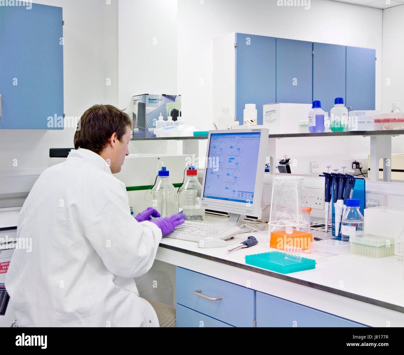 Scienziato lavora sui dati del computer presso il banco da laboratorio Foto Stock