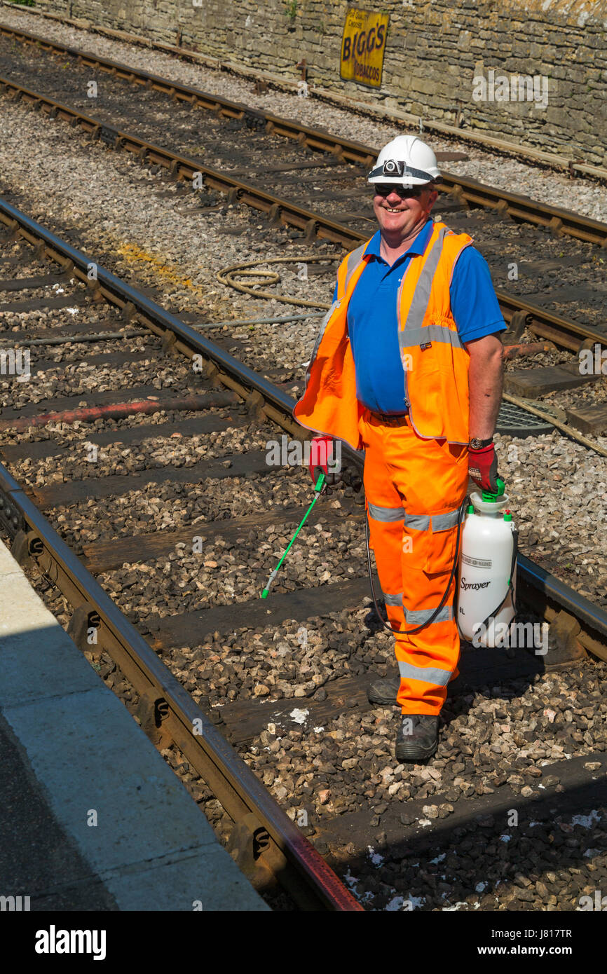 L'uomo la spruzzatura di erbacce lungo i binari ferroviari a Swanage nel Maggio Foto Stock