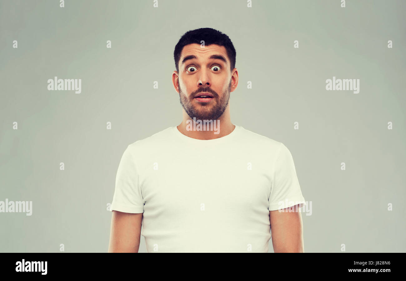 Paura l'uomo in t-shirt bianco su sfondo grigio Foto Stock