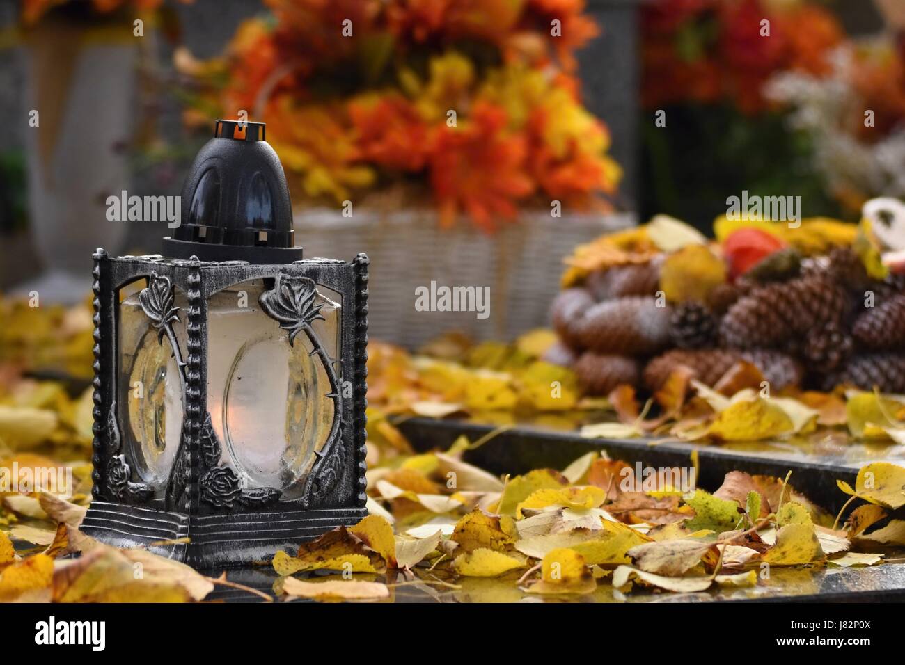 Bellissimo il concetto di autunno per il cimitero e Halloween. Candela in una lanterna sulla tomba. Sfondo per Halloween. Foto Stock