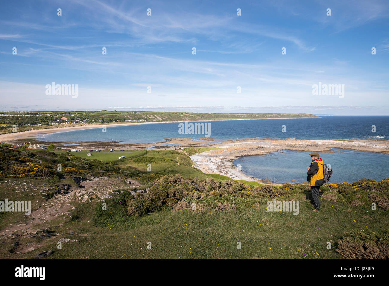 Uomo che cammina sulla costa di Gower verso Port Eynon, Wales, Regno Unito Foto Stock