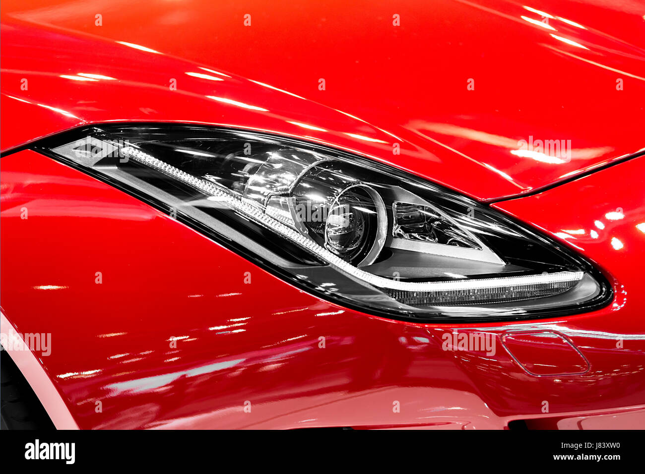 Vista dettagliata del faro per auto a notte. Le luci anteriori della rossa vettura sportiva. Auto della luce. Foto Stock