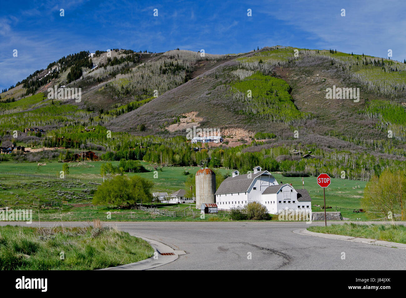 White Barn con silos contro uno sfondo montagnoso. Foto Stock
