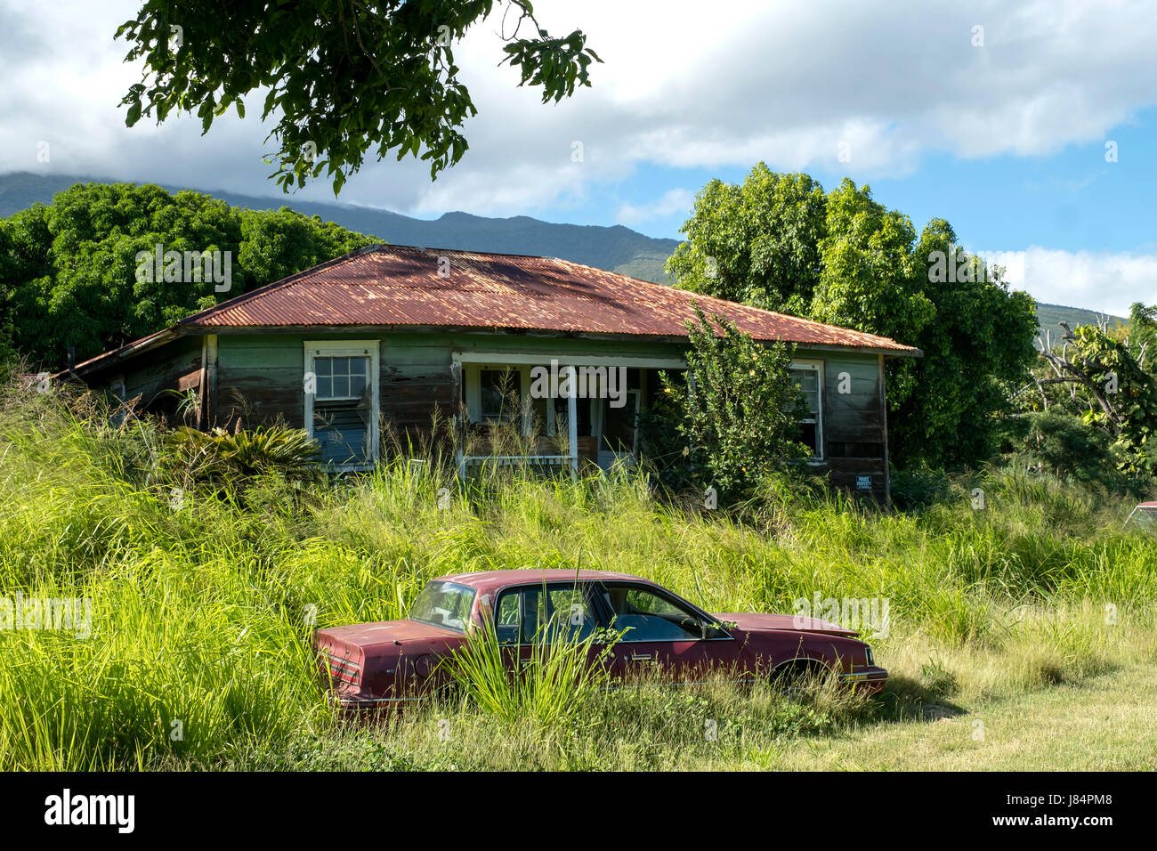 Un auto abbandonate si siede in un cantiere accanto a una proprietà abbandonati appena fuori il pi'ilani autostrada a sud di Maui, Hawaii Foto Stock