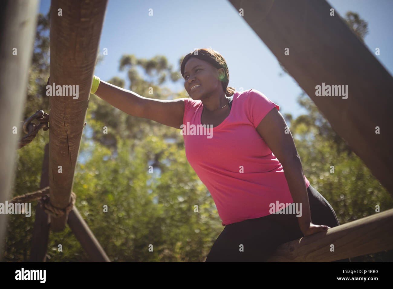 Donna che esercitano su apparecchiature per uso esterno durante la corsa a ostacoli in boot camp Foto Stock