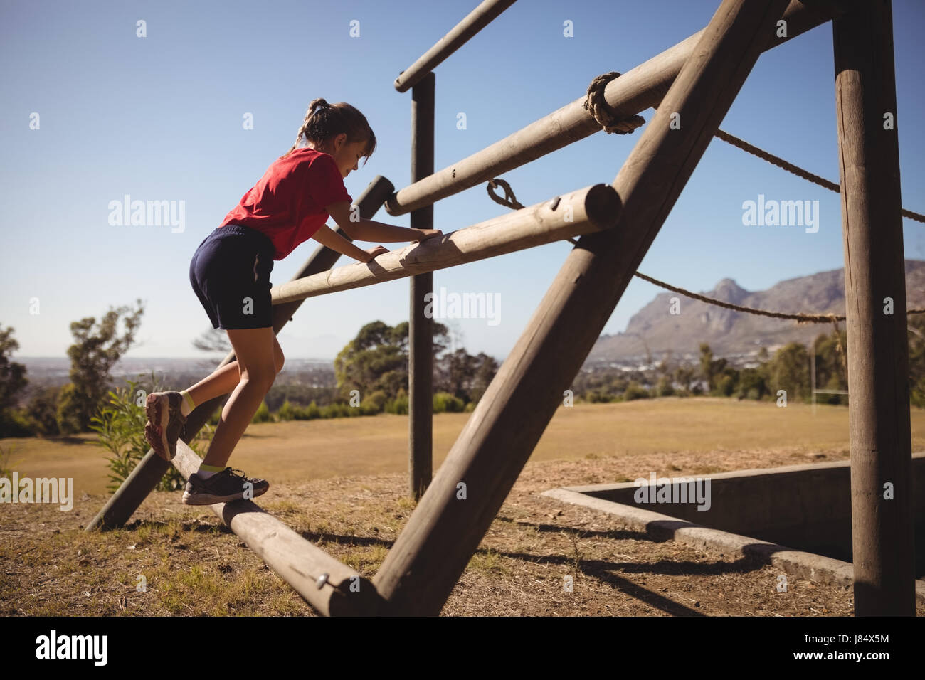 Ragazza esercitando su apparecchiature per uso esterno durante la corsa a ostacoli in boot camp Foto Stock