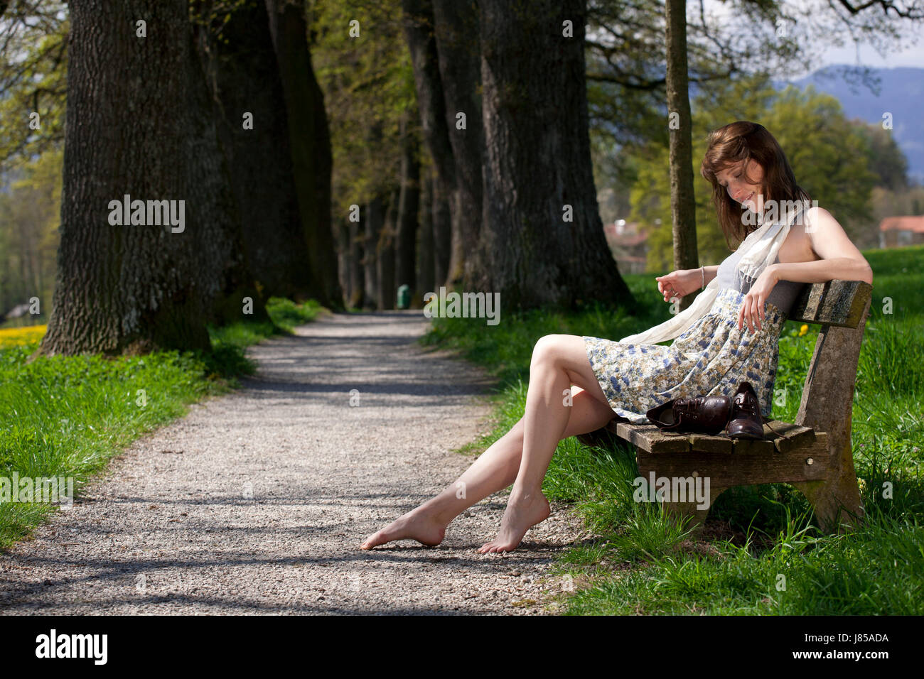 Donna Primavera a piedi nudi giovani giovani sedile unico banco del Parco godendo di donna Foto Stock