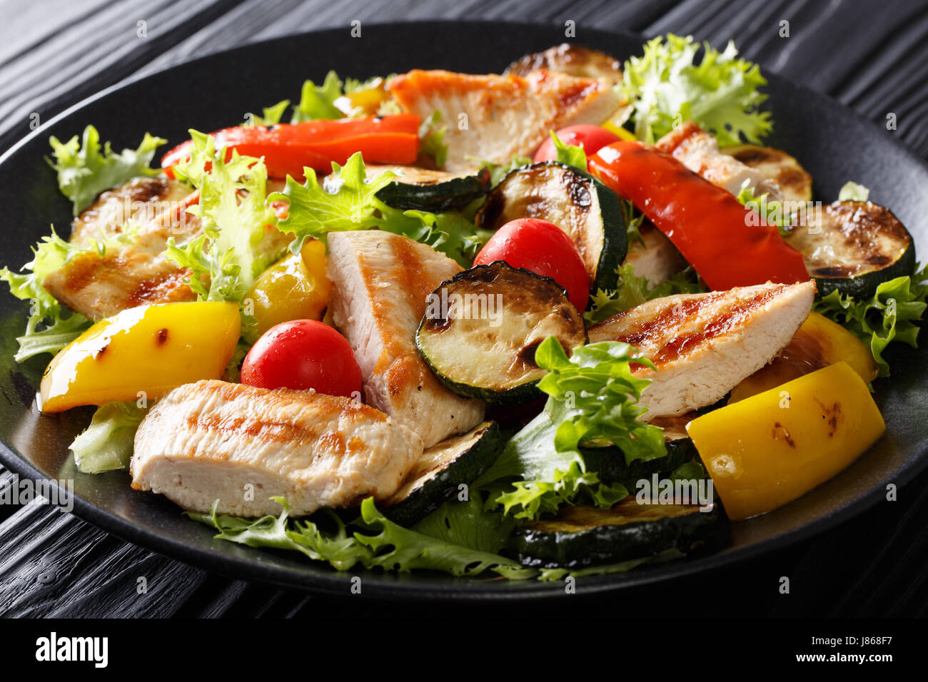 Insalata tiepida di verdure grigliate e pollo close-up su una piastra orizzontale. Foto Stock