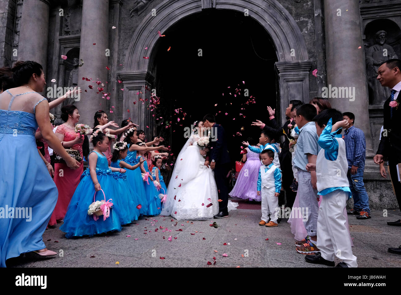 Gli ospiti gettano i confetti sopra la sposa e lo sposo durante un cinese Matrimonio nella chiesa cattolica romana di San Agustin o Iglesia De la Inmaculada Concepcion de Maria de San Agustin situato Situato all'interno della storica città murata di Manila cui si fa riferimento Come Intramuros nella città di Manila capitale del Filippine Foto Stock